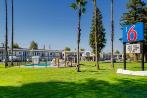 Et motel med swimmingpool, skilt der angiver gratis WiFi, minikøleskab, 3 HBO og ESPN i RMS.
