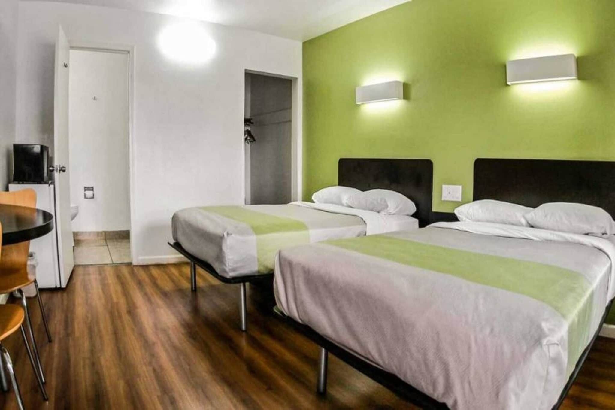 A hotel room with two beds, a desk, and a chair.
