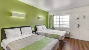 Een hotelkamer met twee bedden, een raam met gordijnen, een deur en een groene muur.