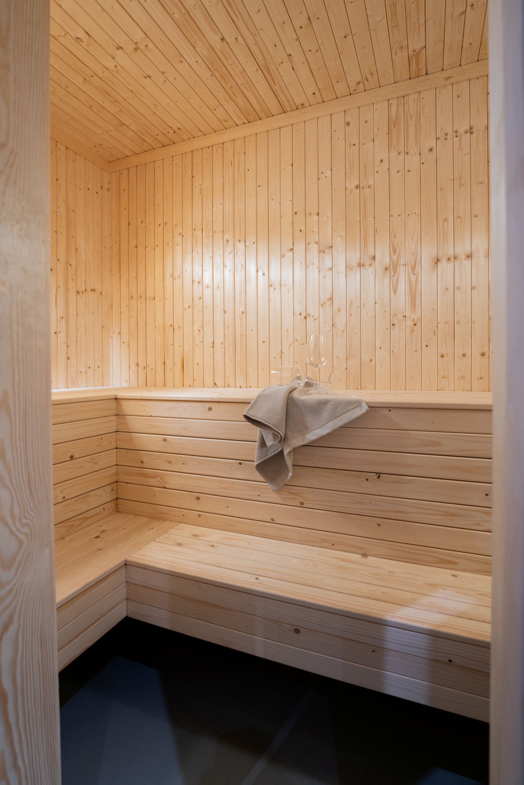 Un sauna avec des bancs en bois et un banc muni d’une serviette.