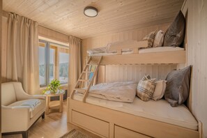 A cozy cabin room with a bunk bed, a chair, a small table with a plant, and a window with a view of trees. - Spacious and modern cabin in Skeikampen (Gudbrandsdalen)