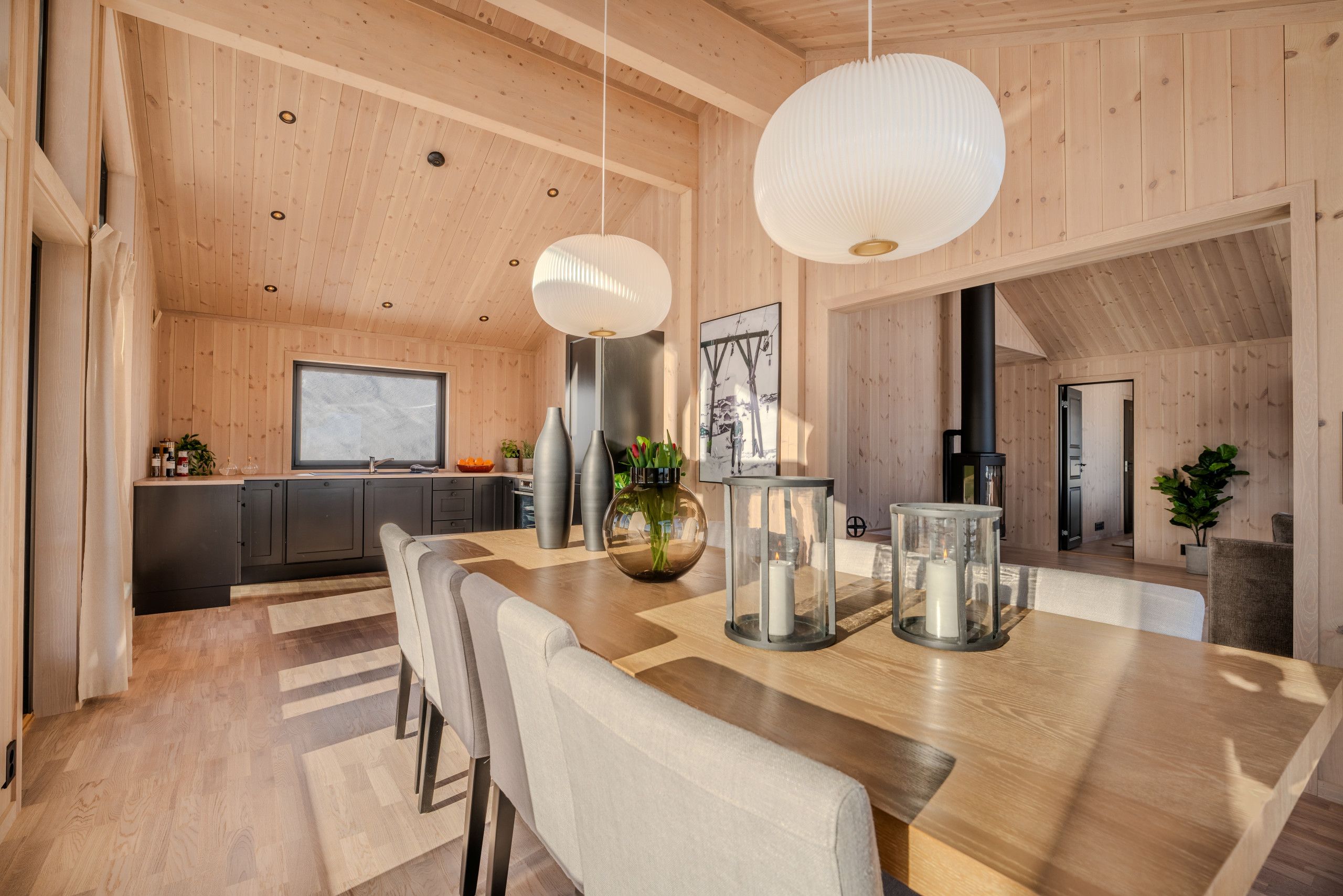 Eine moderne Küche mit Holzwänden, einer großen Kochinsel mit Sitzgelegenheiten und Pendelleuchten.
