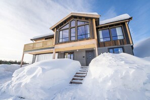 A modern two-story house with large windows and a wooden exterior, surrounded by snow. - Spacious and modern cabin in Skeikampen (Gudbrandsdalen)