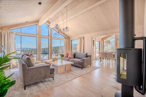 A spacious living room with a large window, a fireplace, and a dining area. - Spacious and modern cabin in Skeikampen (Gudbrandsdalen)