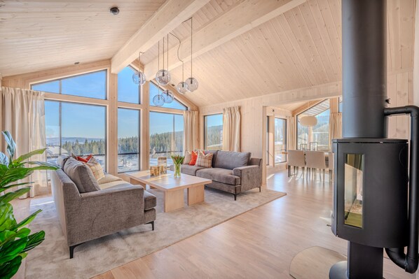 A spacious living room with a large window, a fireplace, and a dining area.