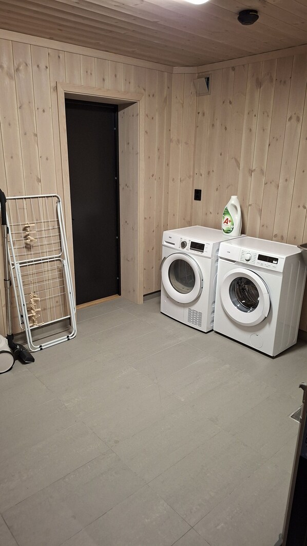 A laundry room with two washing machines, a drying rack, and a bottle of detergent. - Spacious and modern cabin in Skeikampen (Gudbrandsdalen)