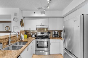 A modern kitchen with stainless steel appliances, granite countertops, and white cabinetry. - Aventura Palm Retreat 2BR  Pool Gym Tennis (Miami)
