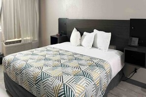 A hotel room with a bed, a bedside table, a nightstand, and a wall-mounted telephone. - 1 King Bed | Non-Smoking, Kitchen (Phoenix)