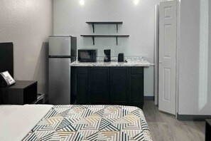 Ein kleines Hotelzimmer mit Bett, Küchenzeile und einer Tür.