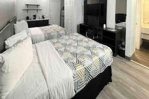 Habitación de hotel con dos camas, un escritorio, un televisor y un armario.