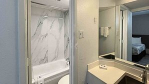 A bathroom with a marble bathtub, a white toilet, a sink, and a mirror reflecting a bed. - 2 Full Beds | Non-Smoking, Kitchen (Phoenix)