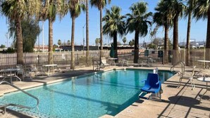 A swimming pool with a clear blue water, surrounded by palm trees and a fenced area with lounge chairs. - 2 Full Beds | Non-Smoking, Kitchen (Phoenix)
