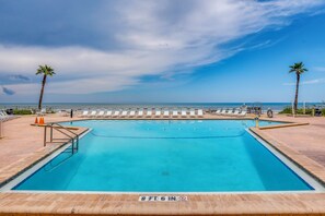 A rectangular swimming pool with a clear blue water surface, surrounded by a tiled deck and white lounge chairs. - Oceanfront Paradise on No-Drive New Smyrna Beach (New Smyrna Beach)