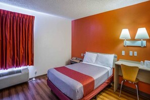 A hotel room with a bed, bedside table, chair, and a window with curtains. - Motel 6 Tucson, Az - North_1 King Bed | (Tucson)