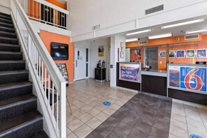 Ein Hotel-Rezeptionsbereich mit Treppe, Empfangstresen und einem an der Wand montierten Fernseher.