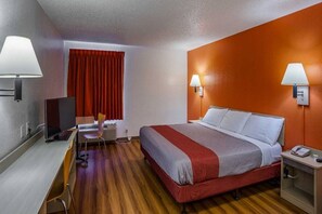 Ein Hotelzimmer mit Bett, Schreibtisch, Stuhl und zwei Wandleuchten.