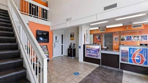 Ein Hotel-Empfangsbereich mit Treppe, Empfangstresen und Wandfernseher.