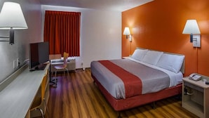 Ein Hotelzimmer mit einem Bett, einem Schreibtisch, einem Stuhl und zwei Wandleuchten.