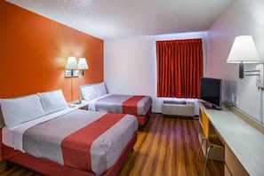 Een hotelkamer met twee bedden, een bureau, een televisie en een raam met gordijnen.