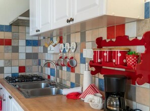 A kitchen with a gas stove, stainless steel sink, and a coffee maker. - Apartment Suzi - Duplex One Bedroom Apartment (Pag)