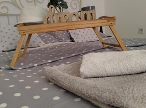 A bed with a polka dot bedspread, a white fluffy blanket, and a wooden tray with a plant and a hat. - Apartment Suzi - Duplex One Bedroom Apartment (Pag)