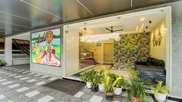 Entrada de um prédio moderno com porta de vidro, plantas em vasos e um mural.