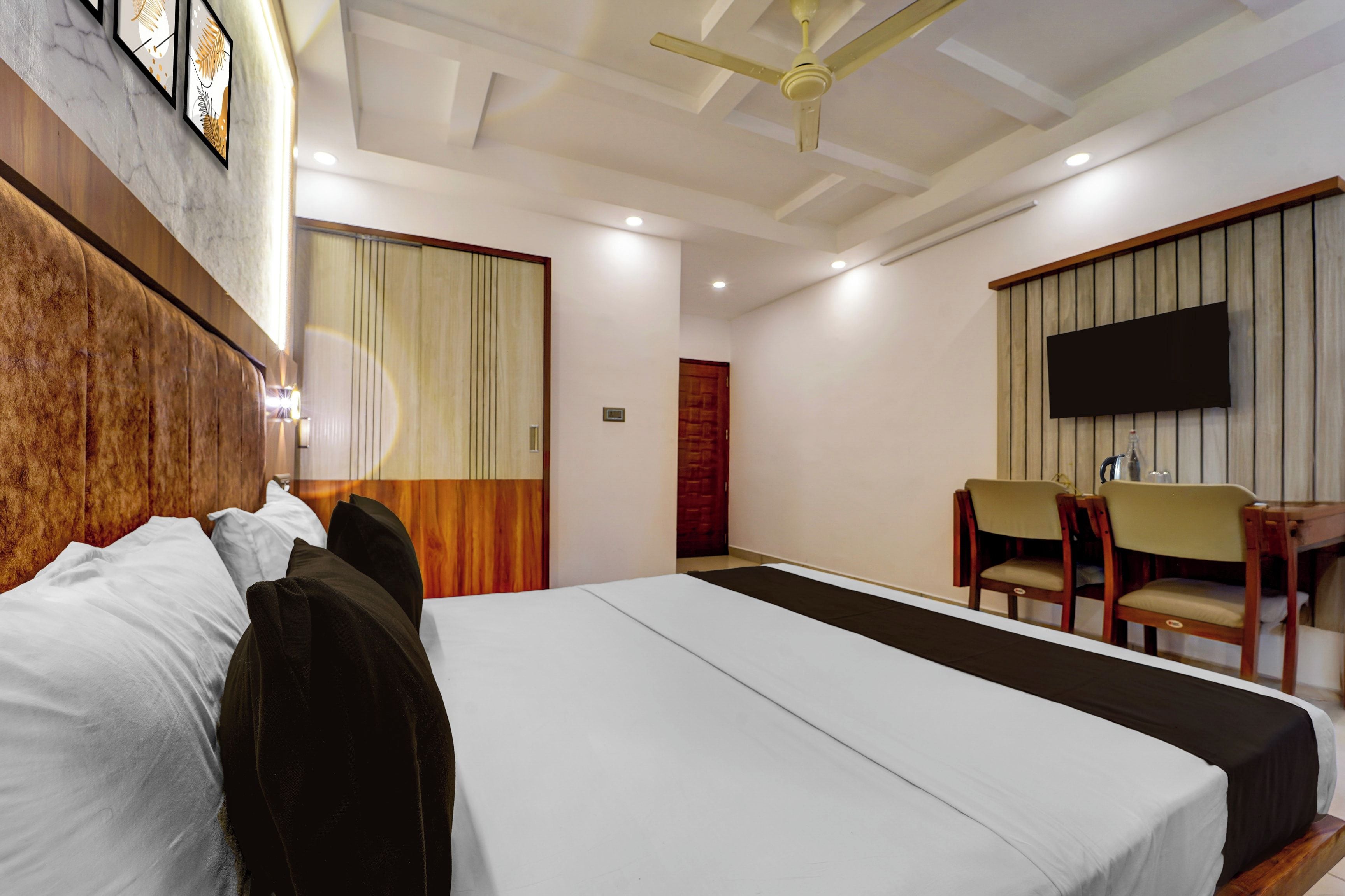 A hotel room with a bed, a desk, a chair, a TV, and a ceiling fan.