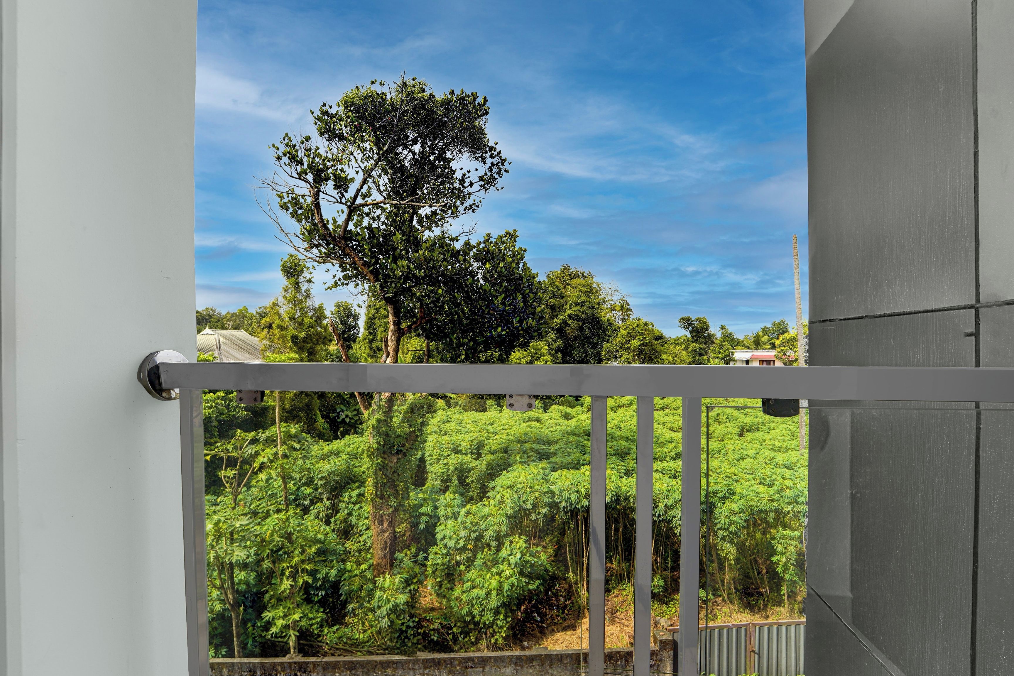 A balcony with a view of a lush green landscape and a clear blue sky.