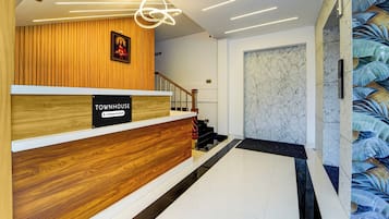 A reception area with a wooden reception desk, a staircase, and a marble wall.