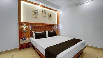 Quarto de hotel com cama grande, cabeceira de madeira, luminárias laterais e luminária fixada na parede.