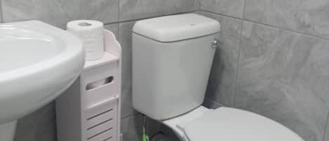 A bathroom with a toilet, sink, and a blue bucket.