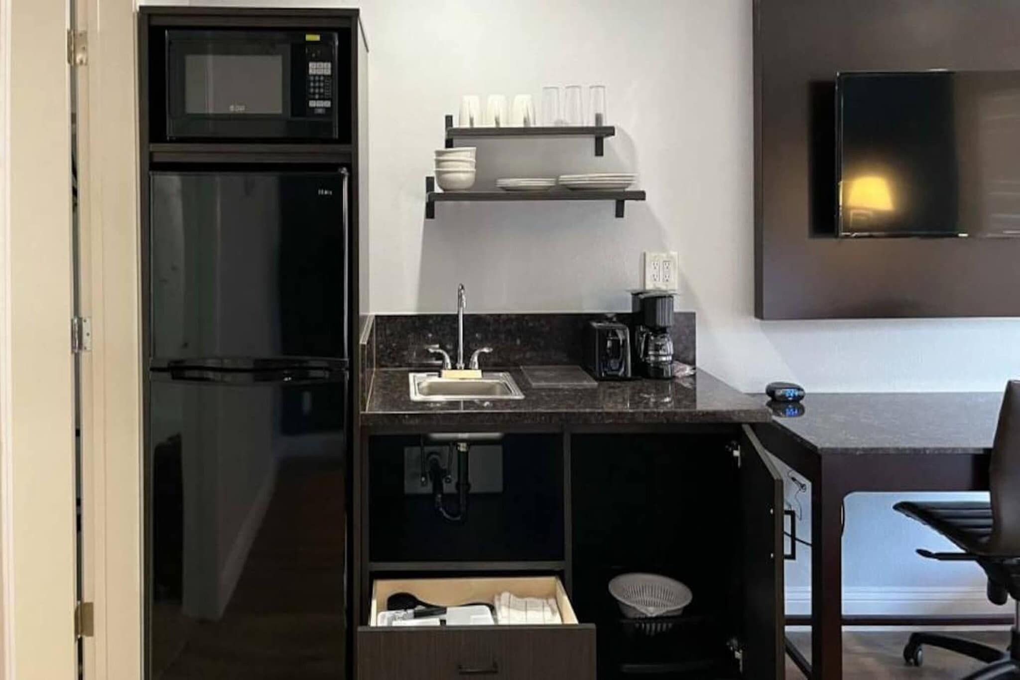 Una kitchenette compacta con microondas, un lavamanos y una cafetera.