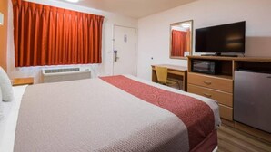 Ein Hotelzimmer mit einem Bett, einem Schreibtisch, einem Fernseher, einer Mikrowelle und einem Kühlschrank.