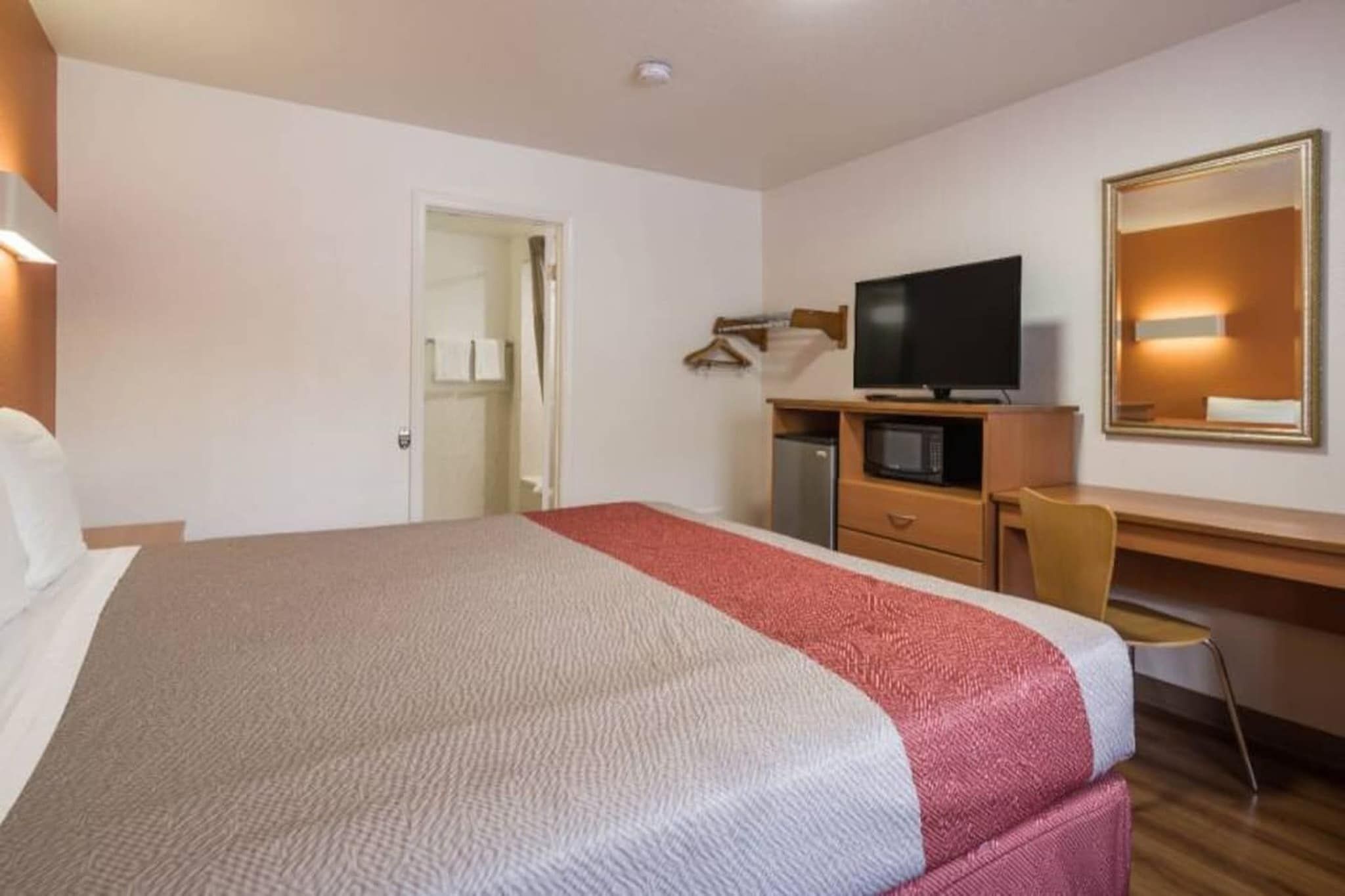 A hotel room with a bed, a desk, a television, and a microwave.