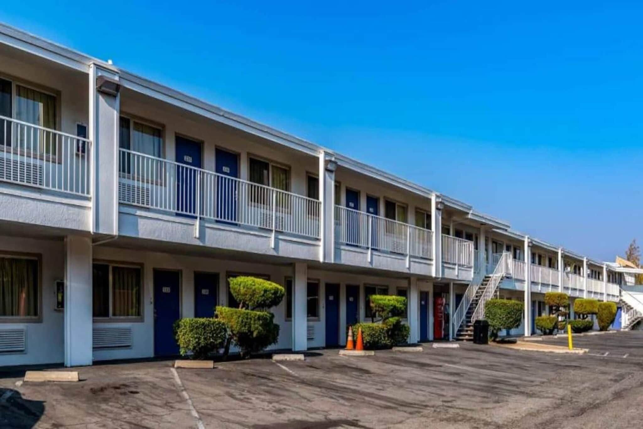 A motel with multiple rooms, a covered parking area, and a staircase leading to an upper level.