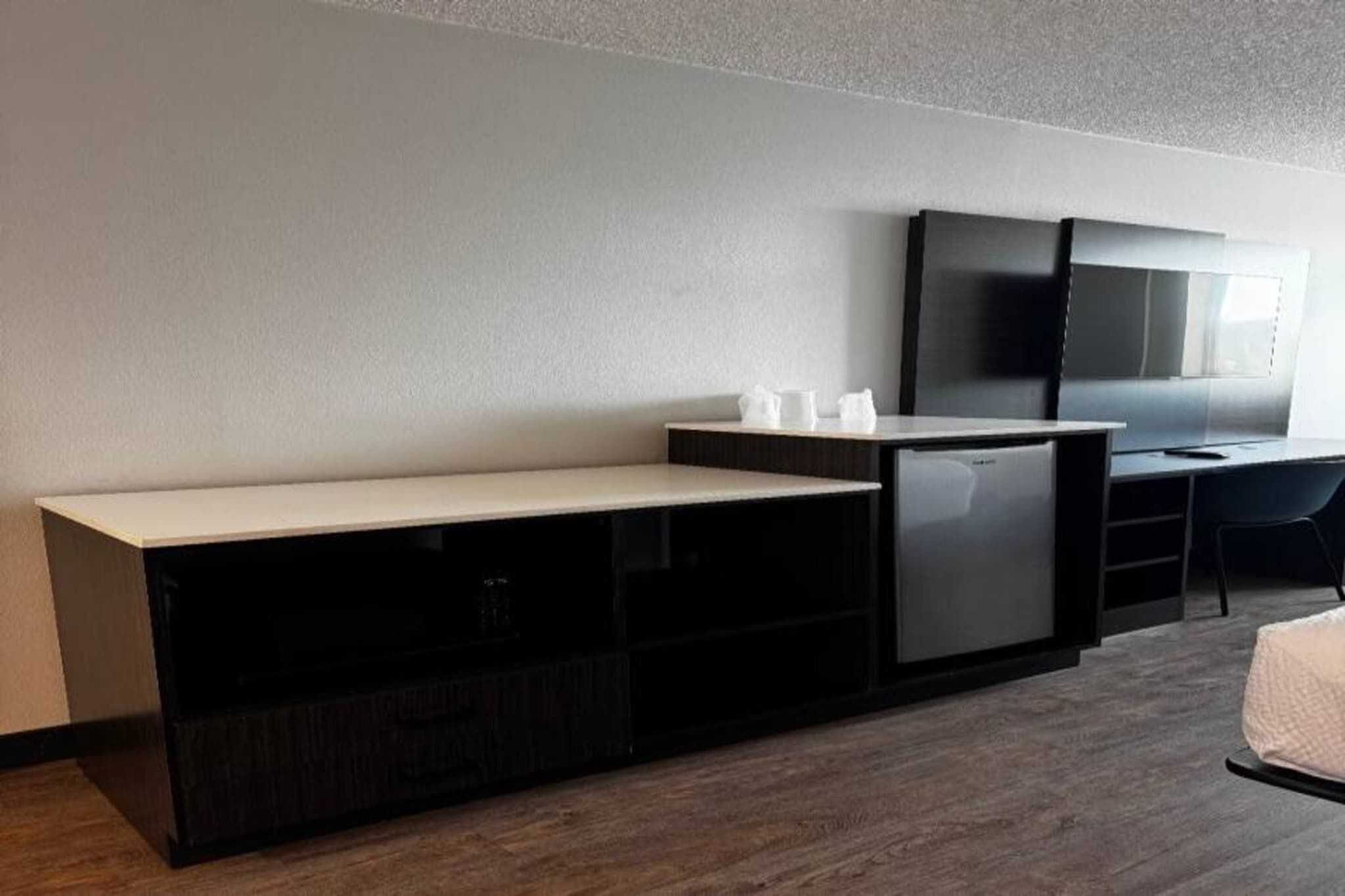 A hotel room with a bed, a desk, a television, and a minibar.