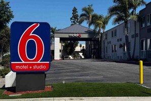 A motel sign with a number 6 and the words 'motel + studio' indicating the establishment. - 2 Queen Beds | Mobil Access Tub Nsmk Micfridg (Carson)