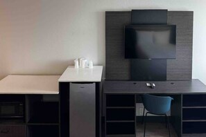 A modern hotel room with a flat-screen TV mounted on a dark wall, a small white table with a chair, and a microwave in the corner. - 2 Queen Beds | Mobil Access Tub Nsmk Micfridg (Carson)