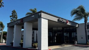 Een motel met een overdekte parkeerplaats en een laag gebouw.