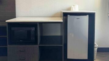 Un angolo cottura con un forno a microonde, un piccolo frigorifero e un piano di lavoro.