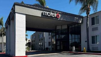 A motel with a covered entrance, palm trees, and a clear sky.