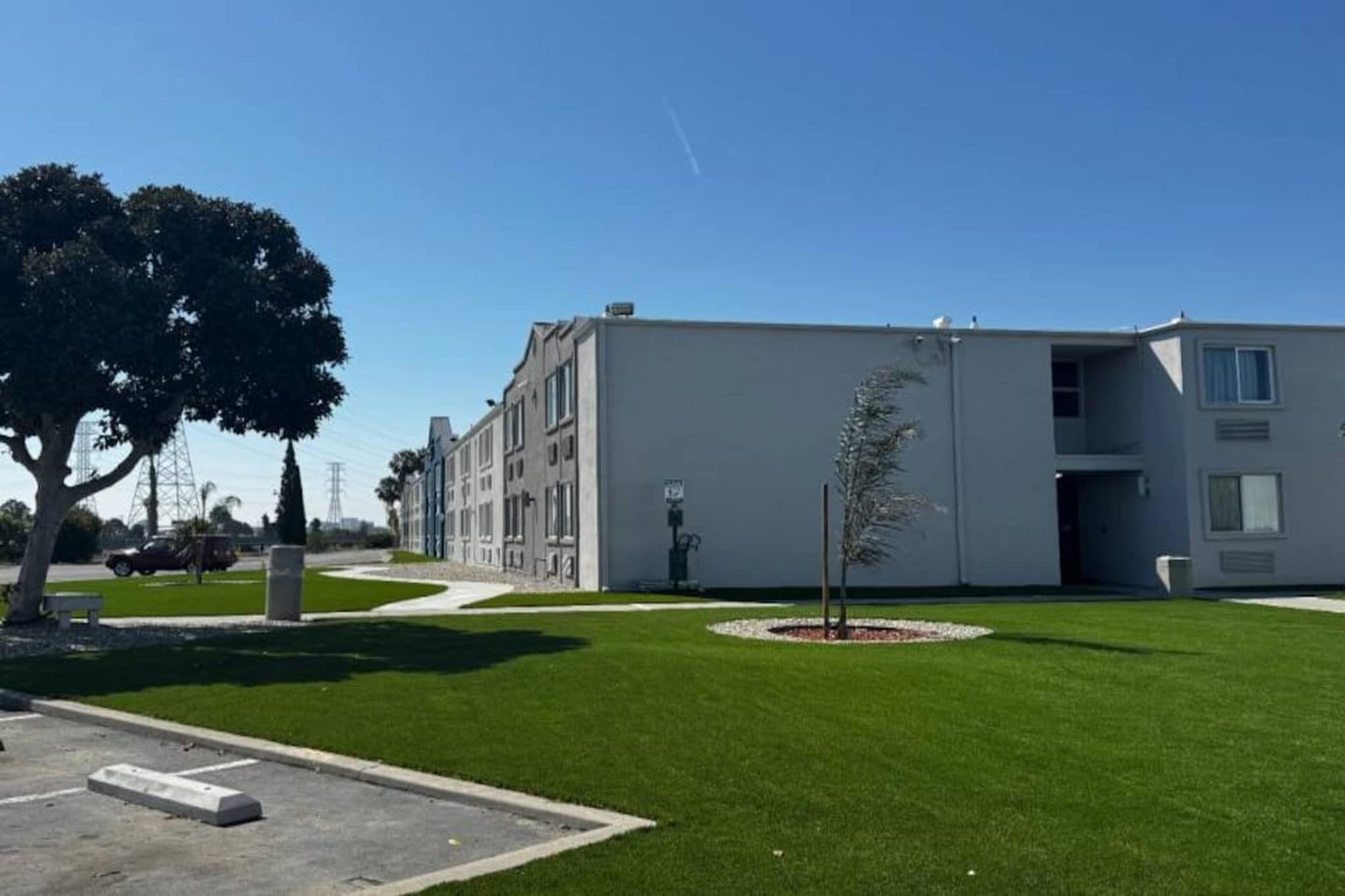 Een modern gebouw met een plat dak, een kleine boom in het midden en een helderblauwe lucht.