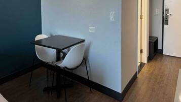 A small room with a table and two chairs, a door, and a light switch on the wall.