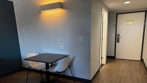 Una stanza con un tavolo, due sedie, una porta e un lampadario a parete.