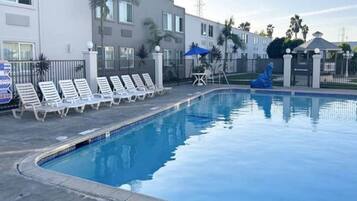 A swimming pool with lounge chairs and a blue umbrella.
