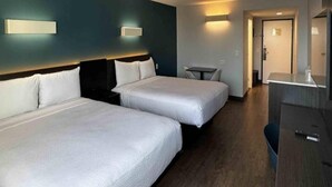 Camera d'albergo con due letti, una scrivania e una sedia.