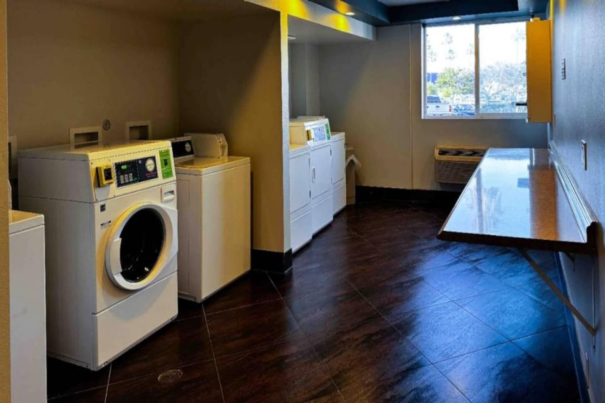 Una sala amb bugaderia, que inclou una rentadora, una assecadora i armaris apilats.