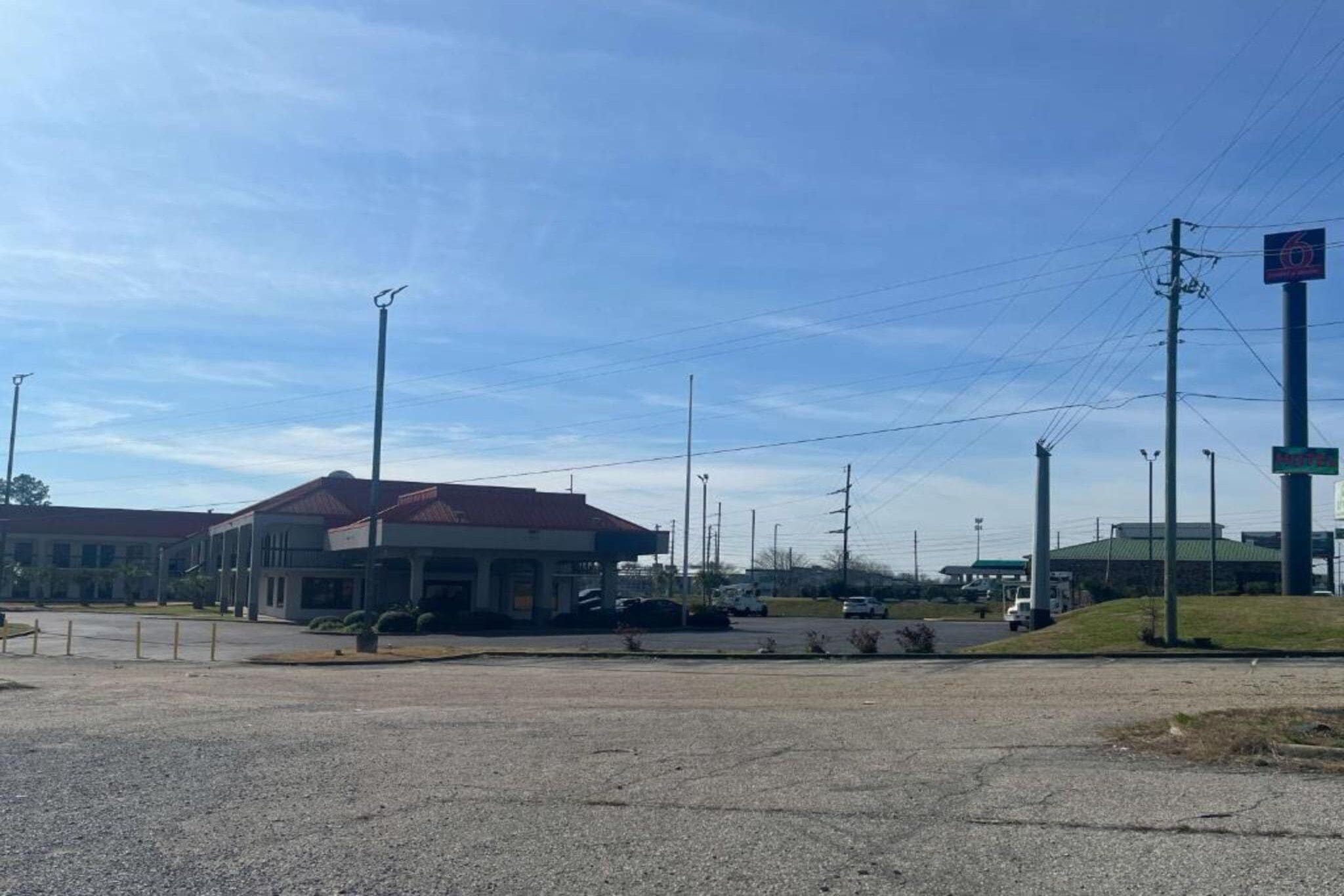 A building with a red roof, a parking lot, and a gas station in the background.
