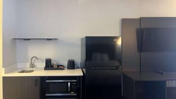 Cuina compacta amb un rentapeus, microones, cafetera i nevera.