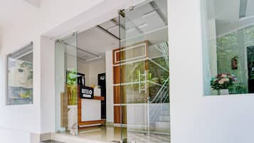 Entrada de un hotel con puerta de vidrio, una recepción y un cartel que dice 'HOTEL'.